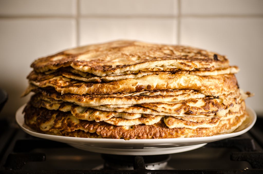 A mouthwatering stack of homemade pancakes on a white plate, perfect for breakfast.