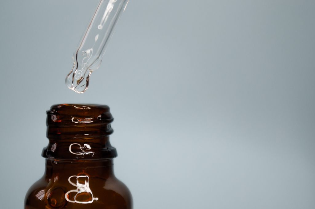 Close-up of a glass dropper with an amber bottle against a neutral background.